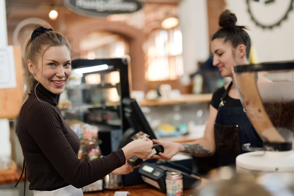 Guest tapping a card to pay at a cafe counter